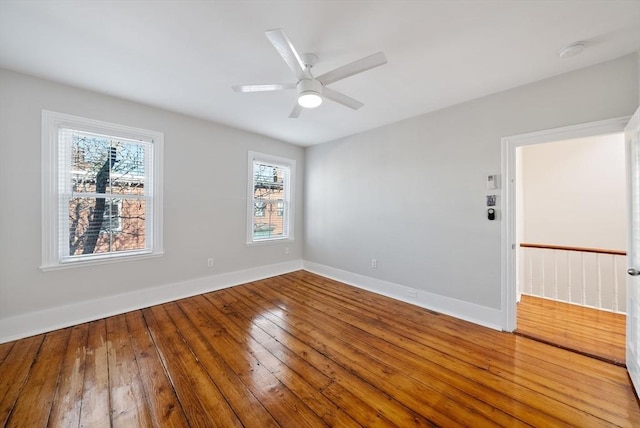 spare room with ceiling fan, baseboards, and wood-type flooring