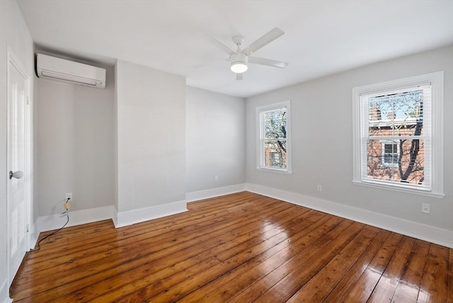 spare room with hardwood / wood-style floors, a ceiling fan, baseboards, and a wall mounted air conditioner