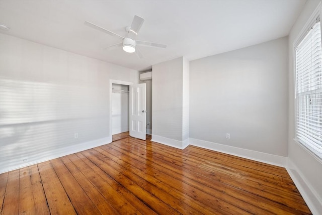 spare room with baseboards, plenty of natural light, an AC wall unit, and hardwood / wood-style floors