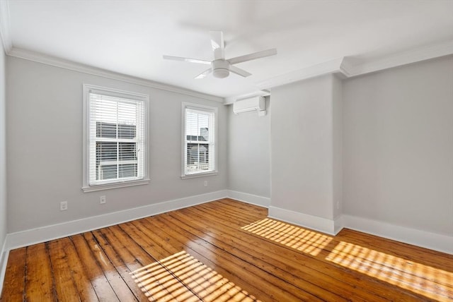 spare room featuring hardwood / wood-style floors, crown molding, baseboards, and a wall mounted AC