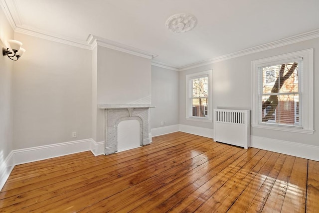 unfurnished living room featuring baseboards, radiator heating unit, a fireplace, wood-type flooring, and crown molding