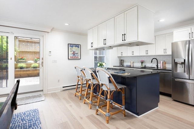 kitchen featuring stainless steel refrigerator with ice dispenser, a sink, a baseboard heating unit, crown molding, and backsplash