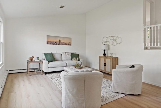 living area featuring a baseboard heating unit, baseboards, visible vents, vaulted ceiling, and wood finished floors