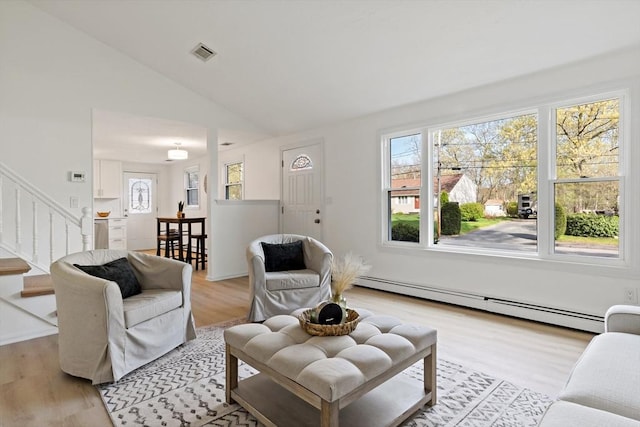 living room featuring light wood-type flooring, visible vents, vaulted ceiling, a baseboard radiator, and stairs