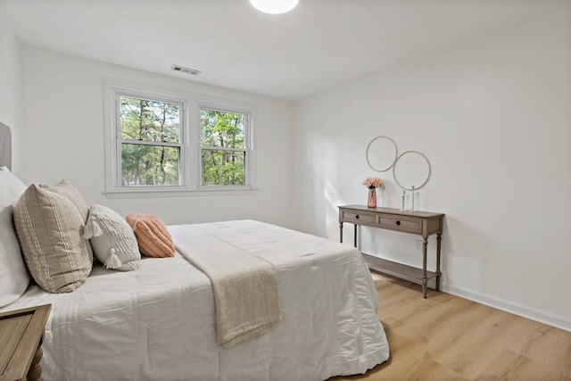 bedroom featuring light wood-style floors, visible vents, and baseboards