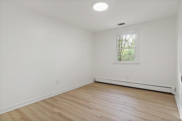 empty room featuring light wood finished floors, visible vents, baseboards, and a baseboard radiator