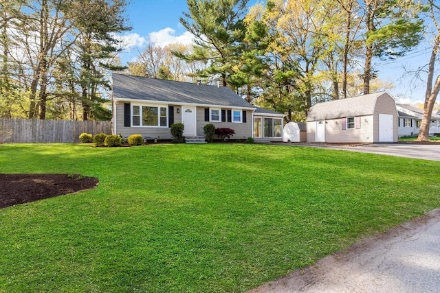 ranch-style home featuring fence, a front yard, an outbuilding, driveway, and entry steps