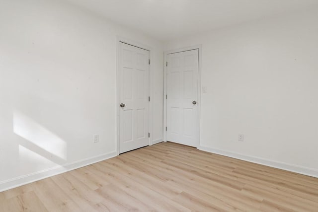 empty room featuring baseboards and light wood-type flooring