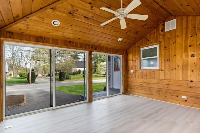 interior space featuring a wealth of natural light, wooden walls, and vaulted ceiling