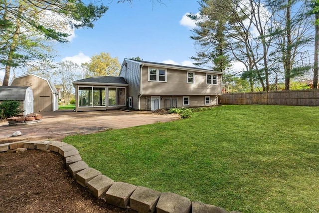 rear view of property featuring a yard, fence, a patio, a shed, and a sunroom