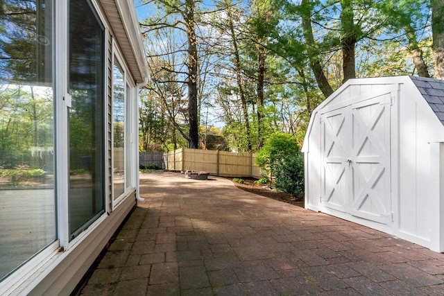 view of patio with fence, a storage shed, and an outbuilding