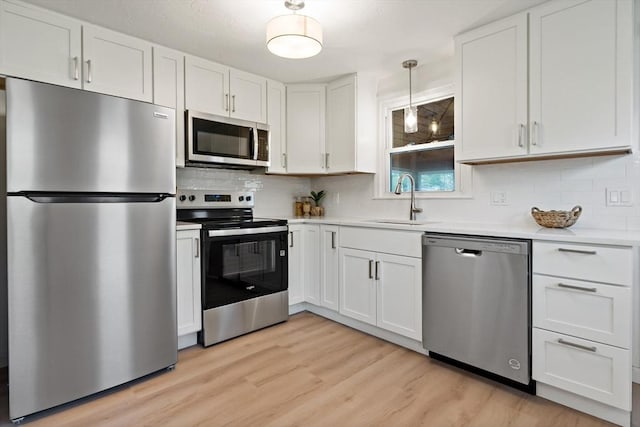 kitchen featuring a sink, stainless steel appliances, light countertops, and white cabinets