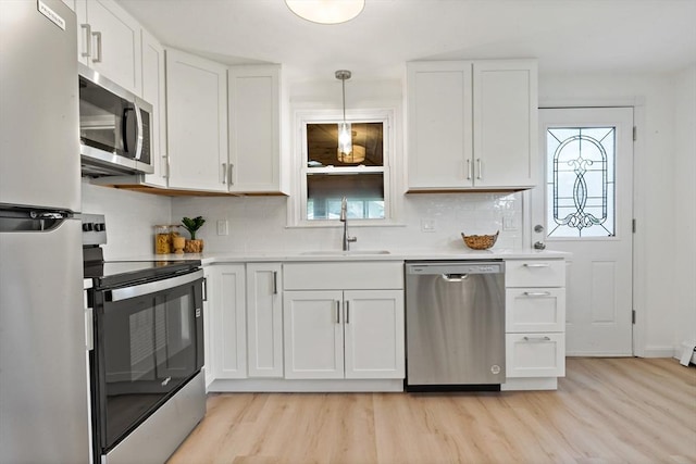 kitchen with a sink, white cabinetry, light wood-type flooring, and appliances with stainless steel finishes