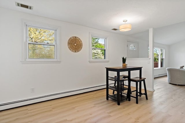 dining space with light wood-style flooring, baseboard heating, and a healthy amount of sunlight