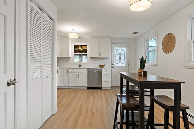 kitchen featuring stainless steel dishwasher, visible vents, a sink, white cabinetry, and light wood-style floors
