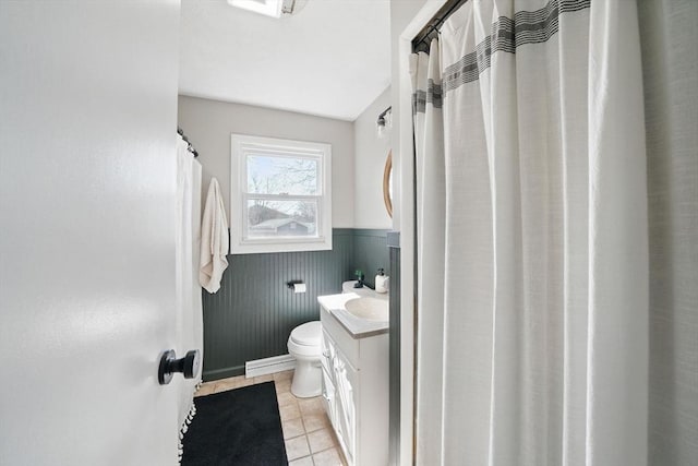 full bathroom featuring toilet, vanity, tile patterned floors, and a wainscoted wall