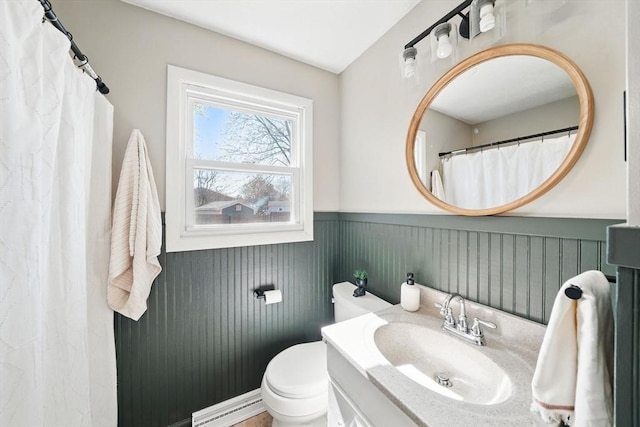 full bathroom featuring a baseboard heating unit, a wainscoted wall, vanity, and toilet