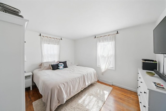 bedroom with baseboards, multiple windows, and light wood-type flooring