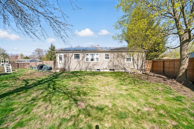 back of property featuring solar panels, a yard, and a fenced backyard