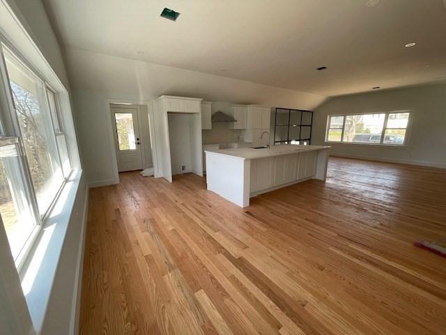 11 Madeline Rd, Falmouth, MA 02536 - kitchen featuring vaulted ceiling, a sink, white cabinets, light wood-type flooring, and light countertops