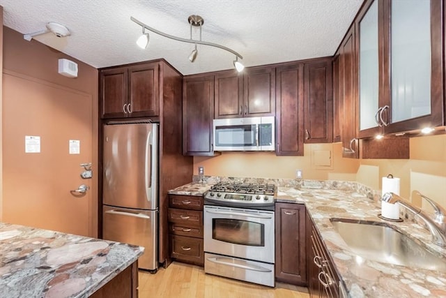 99 Pond Ave Unit 608, Brookline, MA 02445 - kitchen featuring appliances with stainless steel finishes, a sink, light stone counters, light wood-style floors, and a textured ceiling