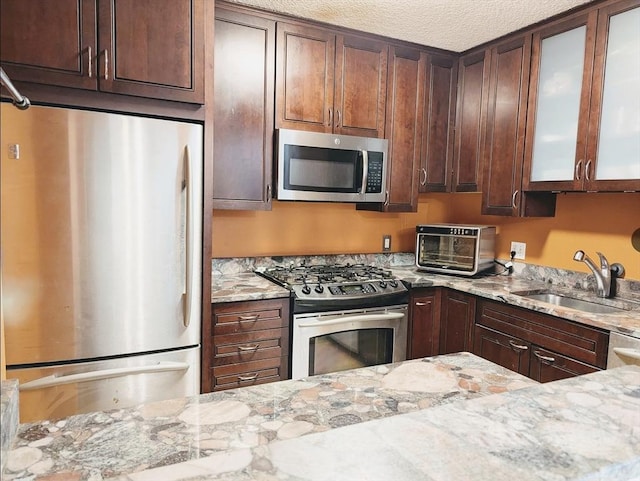 99 Pond Ave Unit 608, Brookline, MA 02445 - kitchen with appliances with stainless steel finishes, a sink, light stone counters, glass insert cabinets, and a textured ceiling