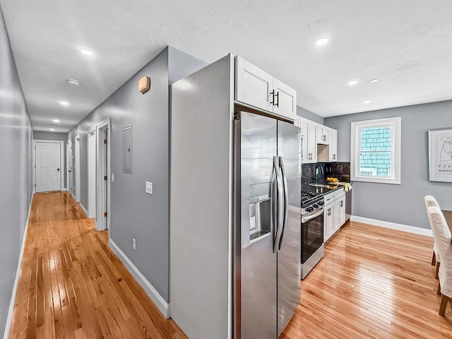kitchen featuring stainless steel fridge, stove, light wood-type flooring, white cabinetry, and recessed lighting