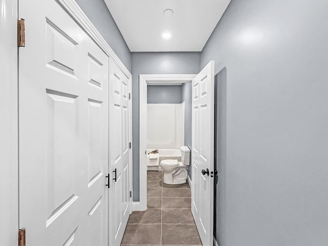 corridor featuring dark tile patterned flooring and baseboards