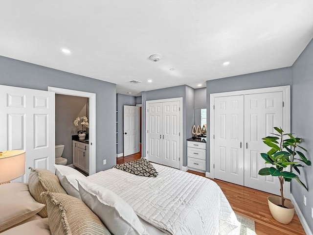 bedroom with multiple closets, wood finished floors, baseboards, recessed lighting, and ensuite bath