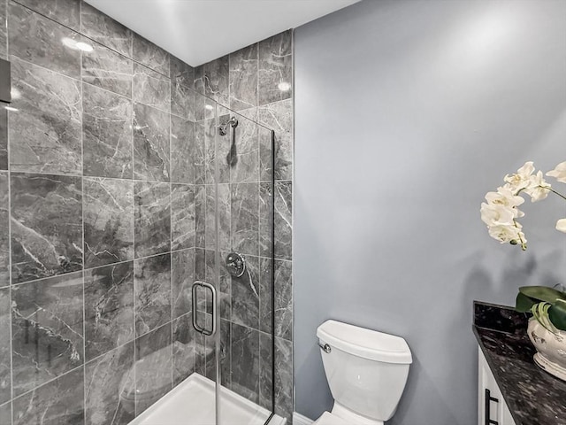 bathroom featuring a shower stall, toilet, and vanity