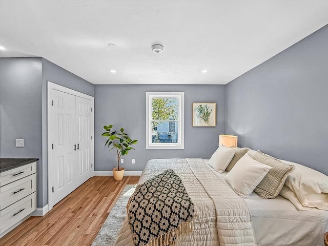 bedroom with light wood-type flooring, baseboards, a closet, and recessed lighting