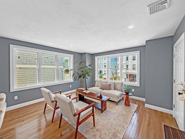 living room featuring light wood-type flooring, baseboards, and recessed lighting