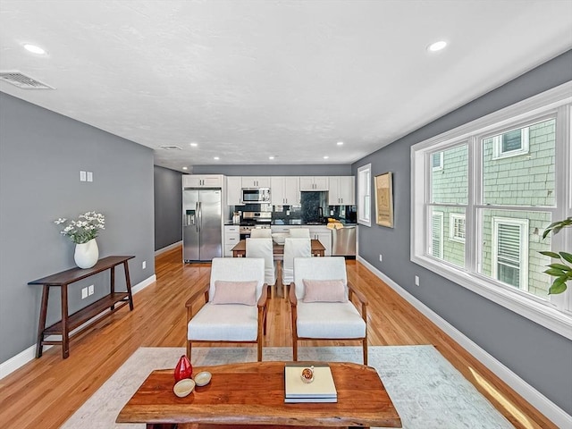 dining area featuring light wood-style flooring, baseboards, and recessed lighting