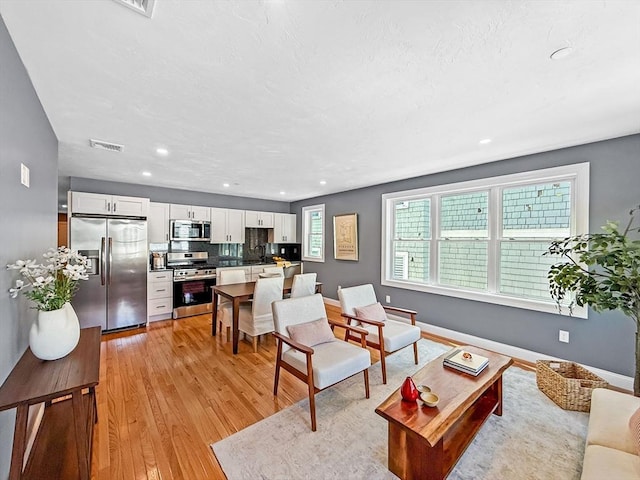 living area with light wood-style floors, recessed lighting, and baseboards
