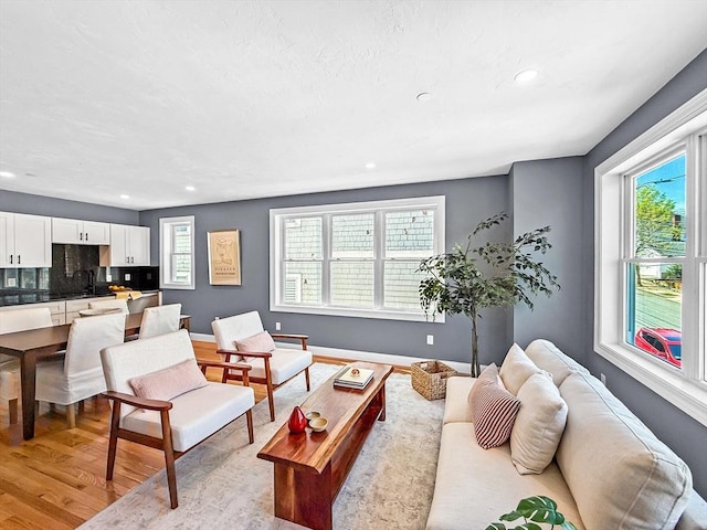living room featuring light wood-style flooring, recessed lighting, and baseboards