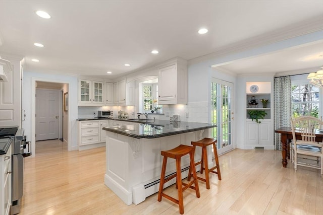 kitchen featuring a sink, ornamental molding, a peninsula, and light wood finished floors