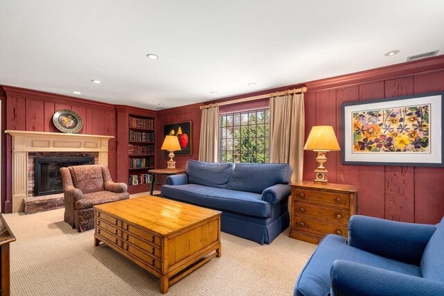 living room with wooden walls, a fireplace with raised hearth, light colored carpet, and recessed lighting