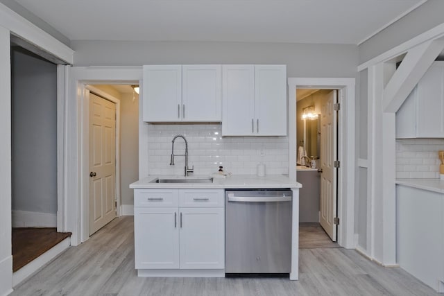 kitchen with sink, backsplash, stainless steel dishwasher, white cabinets, and light wood-type flooring