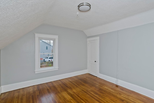 additional living space featuring hardwood / wood-style floors, vaulted ceiling, and a textured ceiling