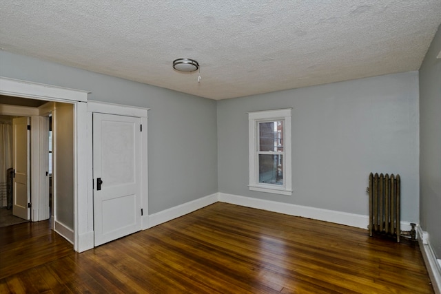 unfurnished room with baseboard heating, dark hardwood / wood-style flooring, a textured ceiling, and radiator