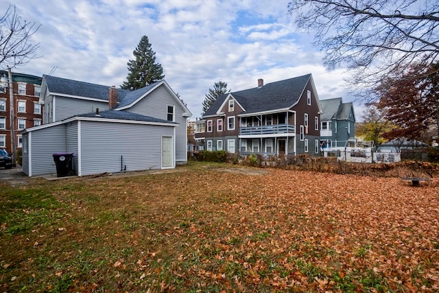 rear view of property with a lawn and a balcony