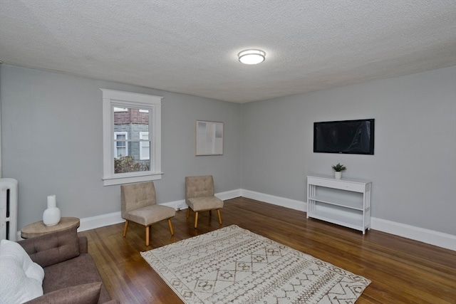 sitting room featuring dark wood-type flooring and a textured ceiling