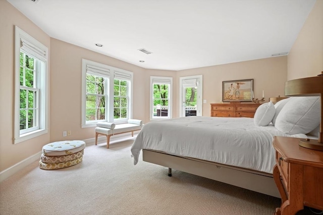 carpeted bedroom featuring access to outside, multiple windows, baseboards, and visible vents