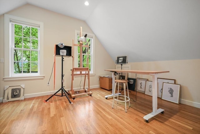 exercise room featuring vaulted ceiling, light wood finished floors, and baseboards