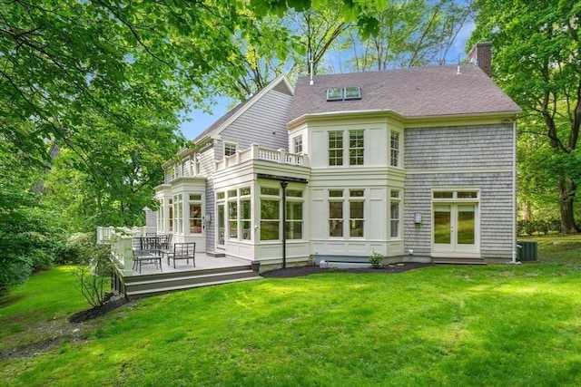 back of house with a lawn, a sunroom, a chimney, a deck, and central air condition unit