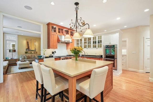 dining area featuring light wood-style flooring, baseboards, a notable chandelier, and recessed lighting