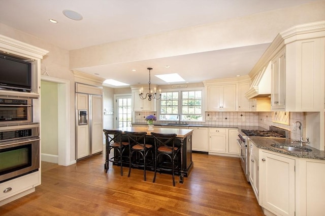 kitchen with sink, a breakfast bar, dark stone countertops, a center island, and premium appliances