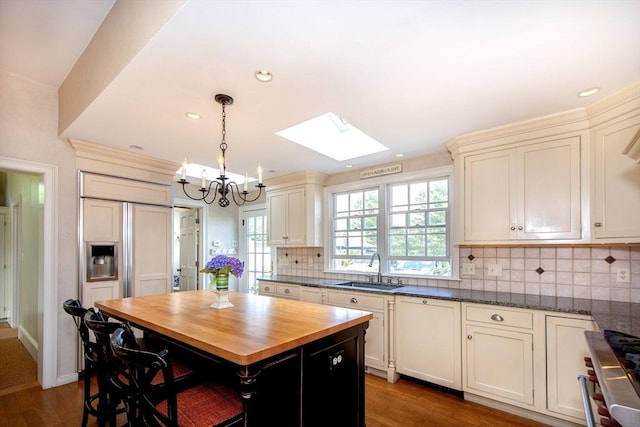 kitchen with wood counters, stainless steel range oven, sink, a center island, and pendant lighting