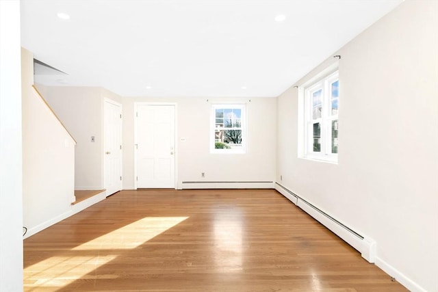 unfurnished room with wood-type flooring and baseboard heating