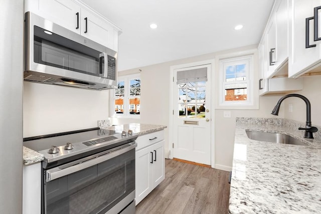 kitchen with light stone countertops, appliances with stainless steel finishes, sink, and white cabinets